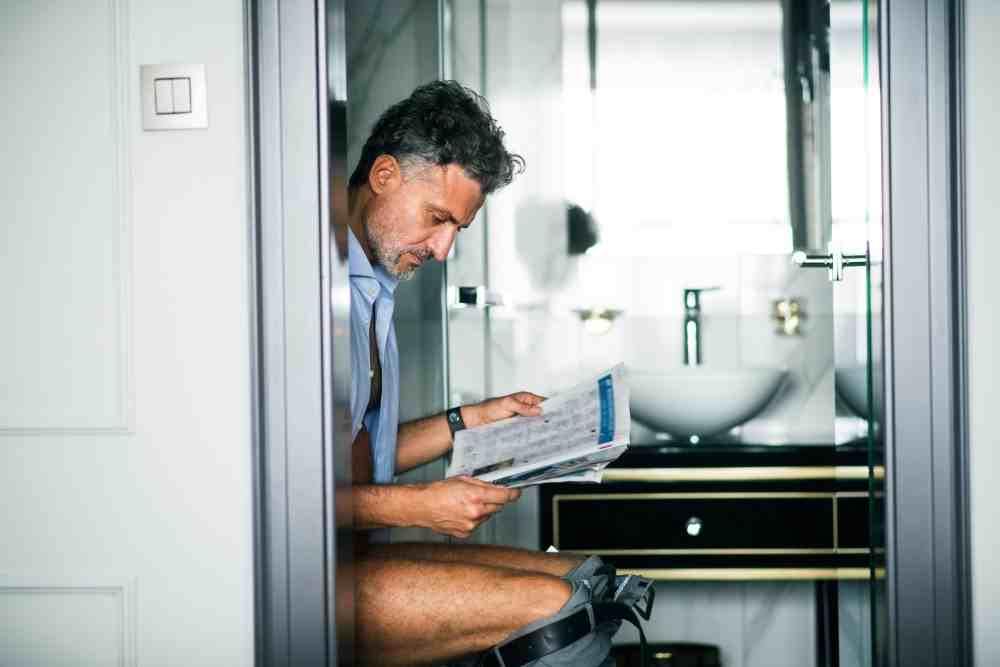 Présentation d'un homme constipé sur les toilettes ayant bu du jus de pruneaux
