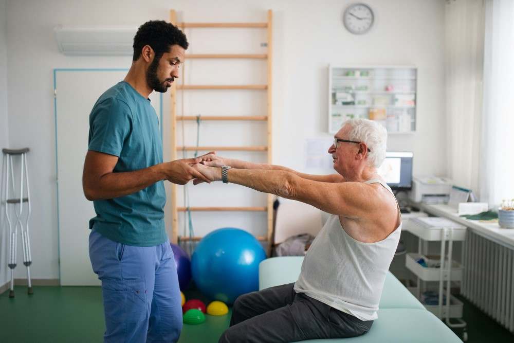 Kinésithérapeute faisant de la rééducation avec son patient atteint du syndrome de Guillain-Barré