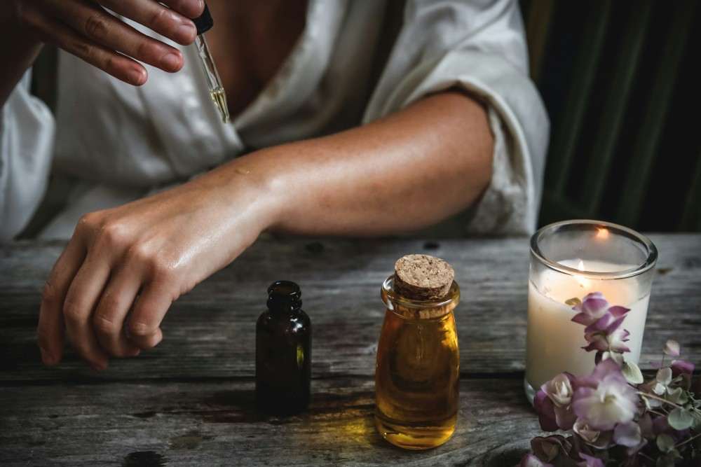 Quelle huile essentielle pour le rhume la toux le nez bouché, femme mettant de l'huile sur sa peau