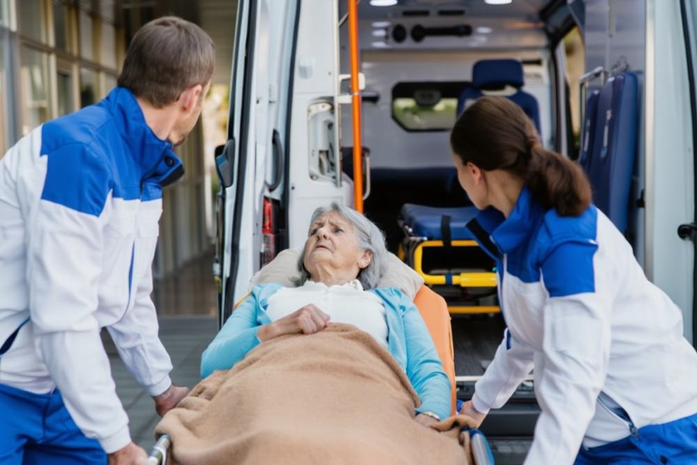 Transport allongé pour une dame âgée avec deux ambulanciers