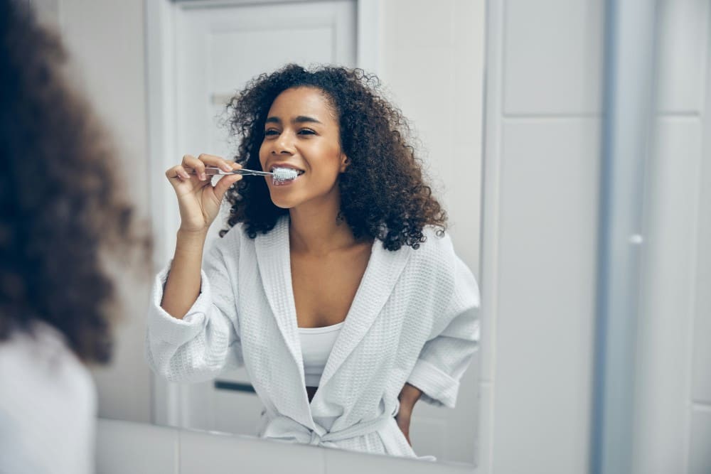 Femme devant le miroir qui se brosse les dents