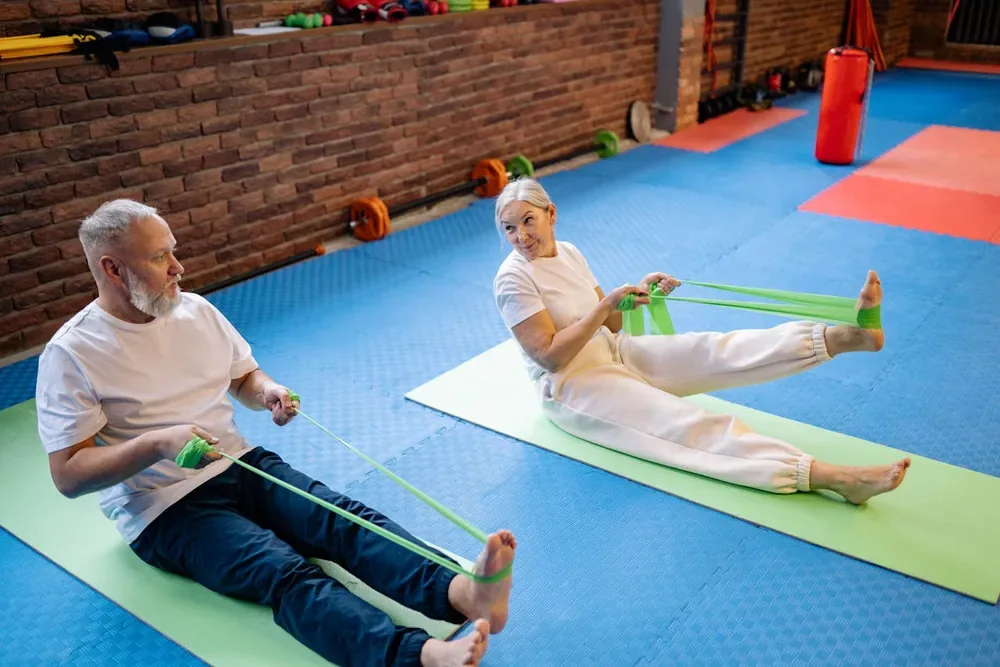 Couple senior renforçant ses muscles avec des bandes élastiques pour lutter contre l'ostéoporose