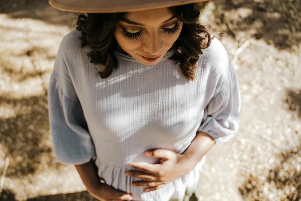 Tiraillement bas-ventre début de grossesse 1 semaine : femme tenant son ventre lors d'une promenade en extérieur