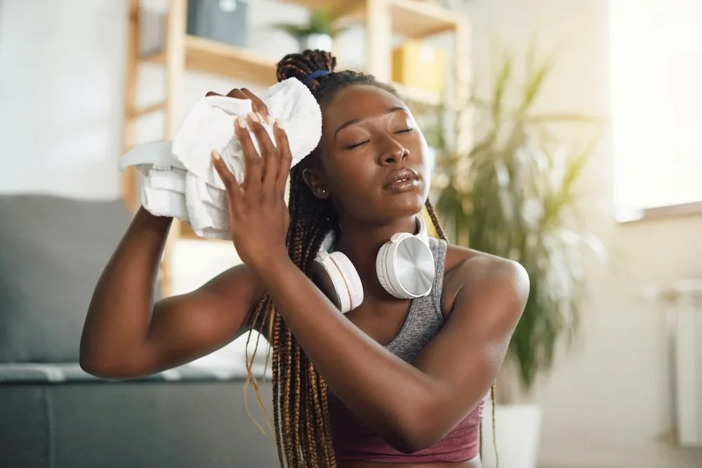 Femme qui a chaud après le sport et qui s'essuie le visage avec une serviette