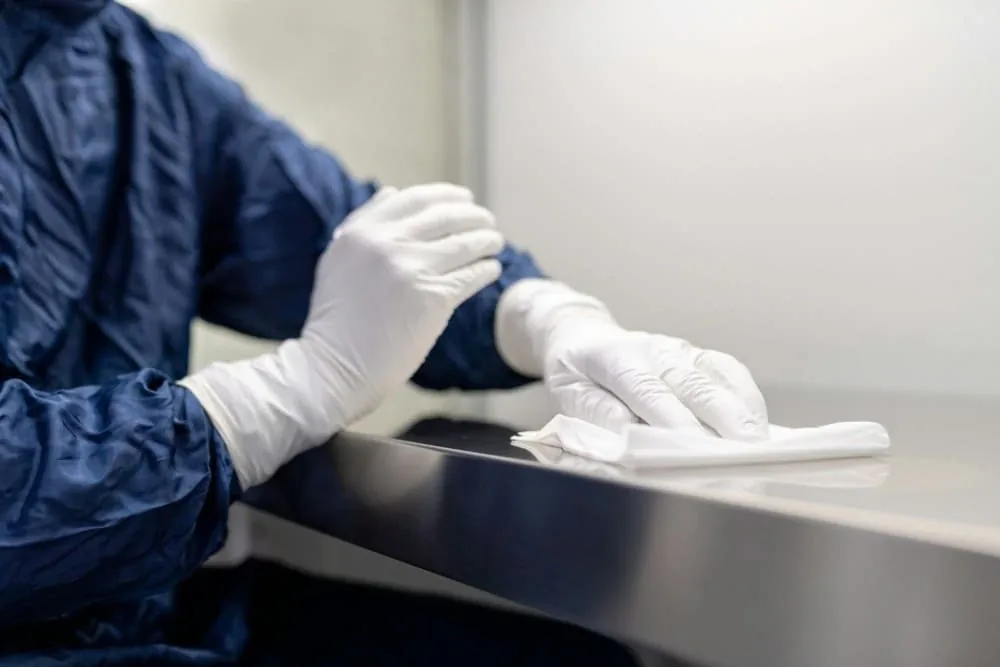 Agent appliquant un désinfectant de nettoyage sur une surface médicale avec une lingette