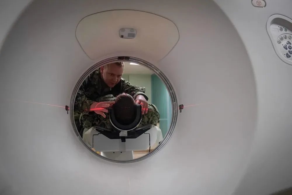 Un homme en uniforme militaire ajuste la position de la tête d'un patient