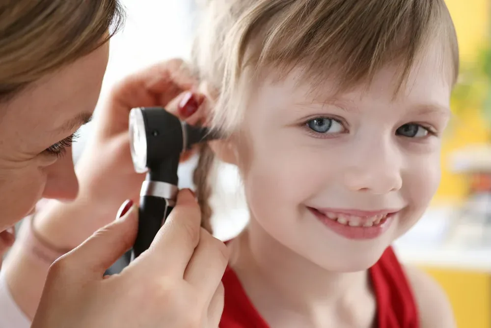 Diabolo dans les oreilles : une soignante examine l'oreille d'un jeune enfant à l'otoscope